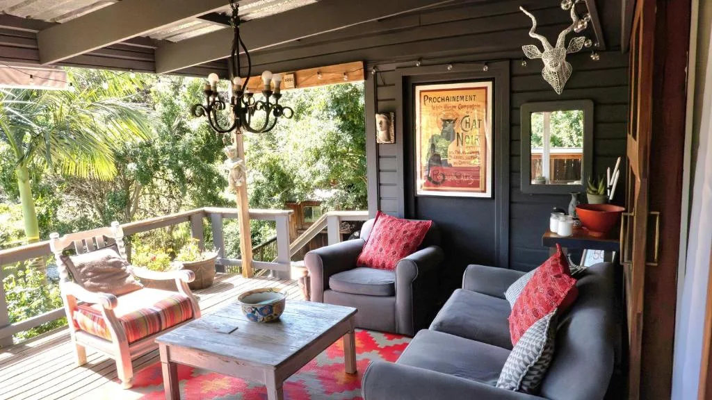Covered deck with lounge seating, armchair, and garden views beyond