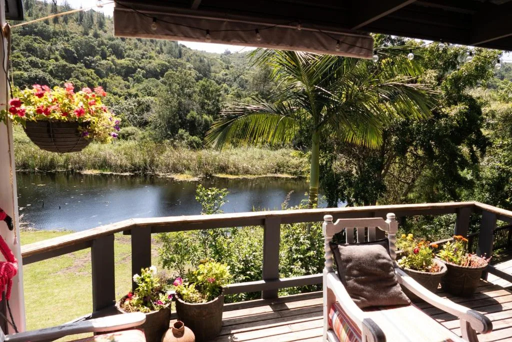 Shaded riverfront deck with lounge chairs overlooking lush garden valley