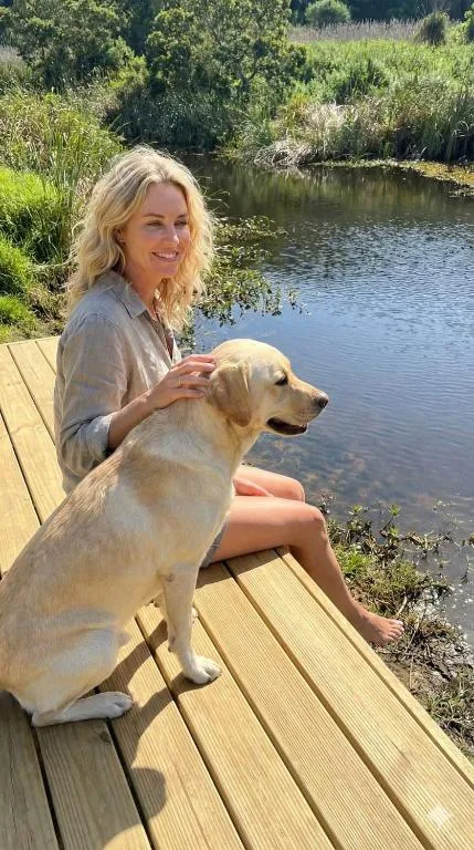 Woman with dog relaxing on wooden deck overlooking tranquil river