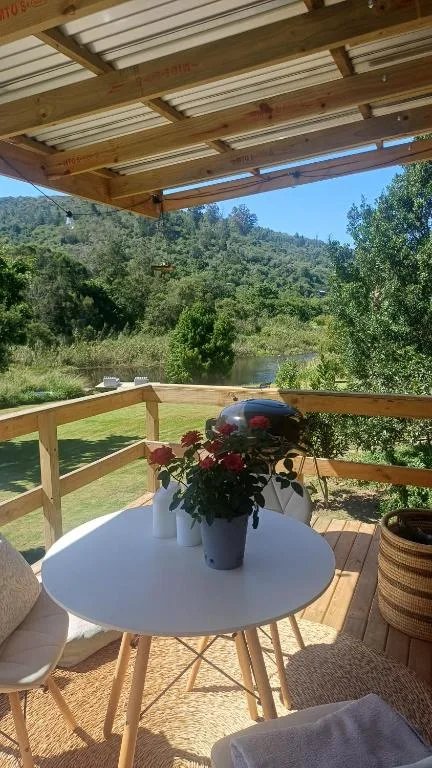 Covered deck with white table overlooking river and forested hills
