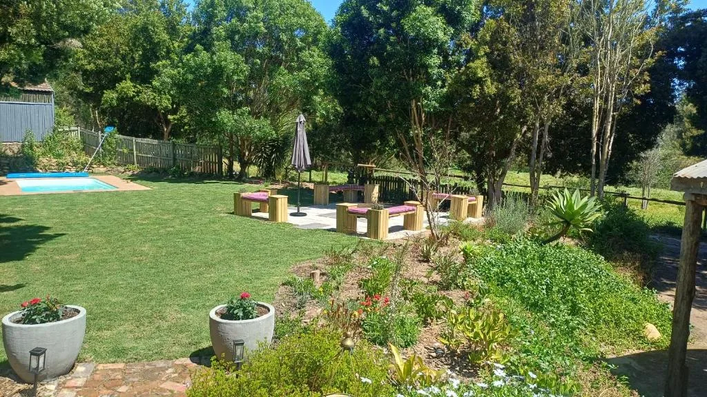 Spacious garden with wooden benches, pool, and mature trees
