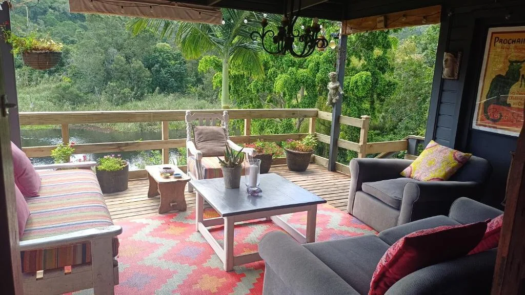 Covered wooden deck with seating, furniture, and lush garden views