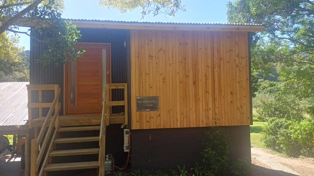 Modern wooden cabin with corrugated metal roof and wooden entrance stairs