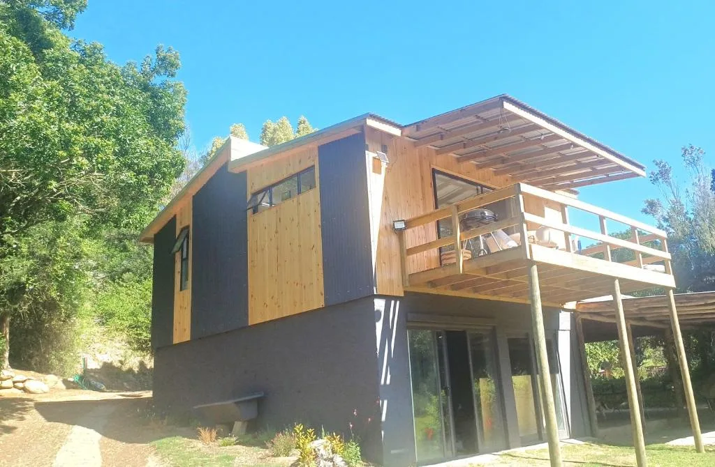 Modern wooden cabin with deck overlooking lush garden surroundings