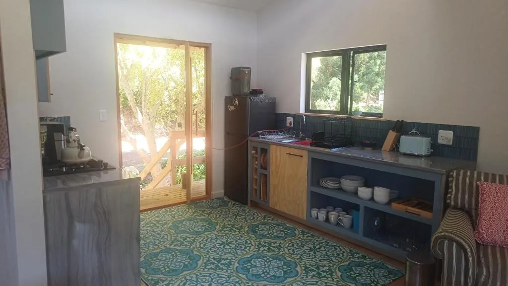 Kitchen with dark cabinetry, open shelving, and garden views through glass doors
