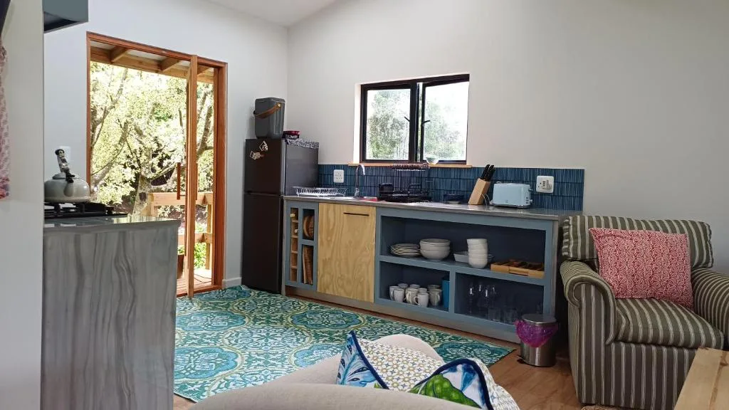 Modern kitchen with blue tiled backsplash, wooden cabinetry, and outdoor garden views