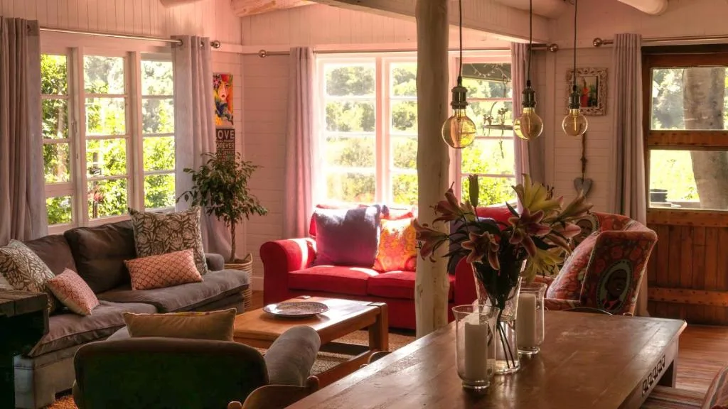 Bright lounge with red sofa, gray seating, pendant lights, and garden views