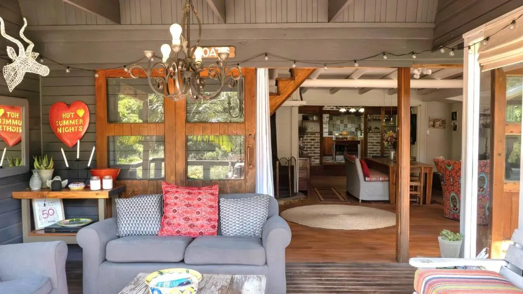 Bright lounge with gray sofa, colorful cushions, wooden beams, and garden views