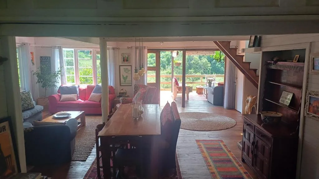 Spacious open-plan lounge with red sofa, dining table, and garden views