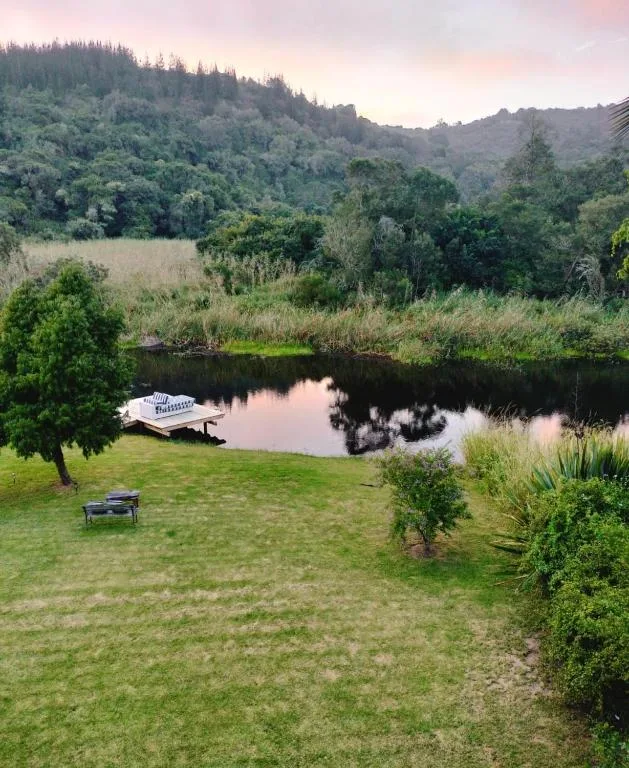 Peaceful river lagoon view surrounded by green lawns and forested mountains