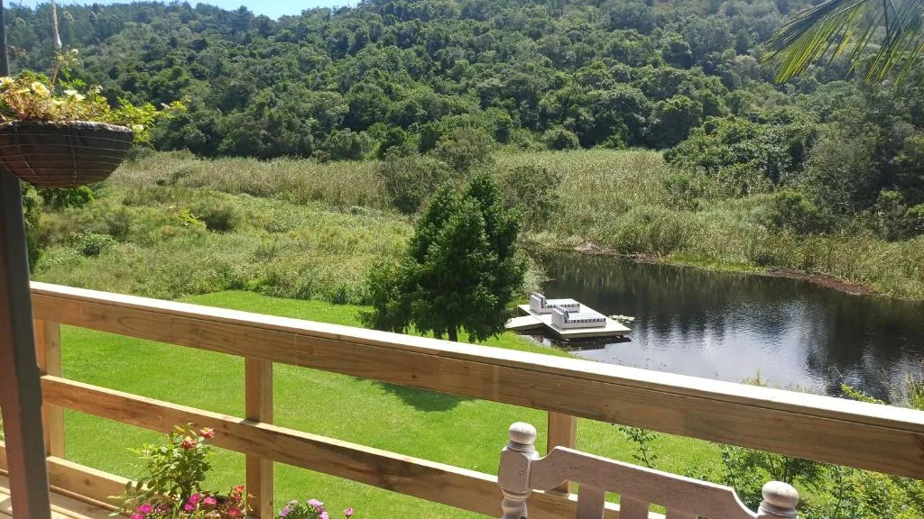 Scenic lagoon view with lush green gardens and forested hills beyond