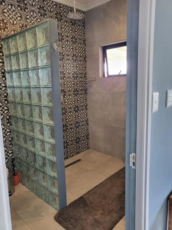 Modern shower enclosure with decorative tilework and glass brick feature wall