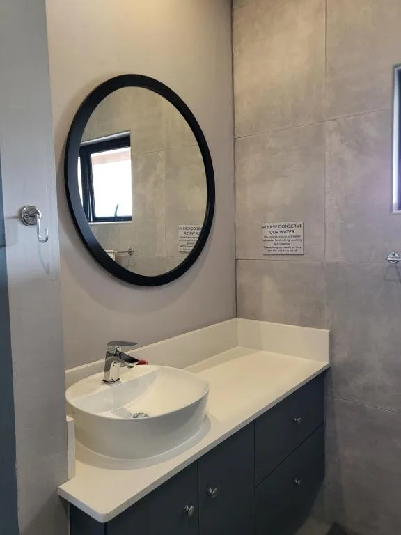Modern bathroom with round black mirror above white vanity sink
