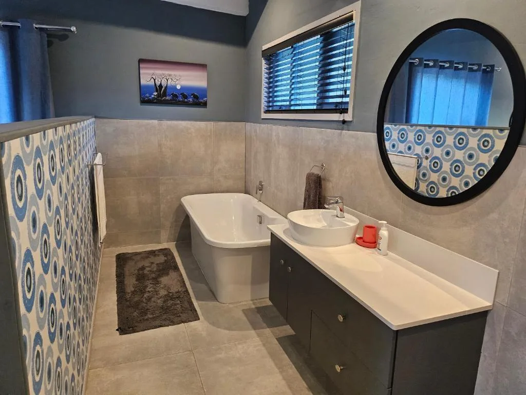 Modern bathroom with freestanding tub, double vanity, and decorative circular mirror