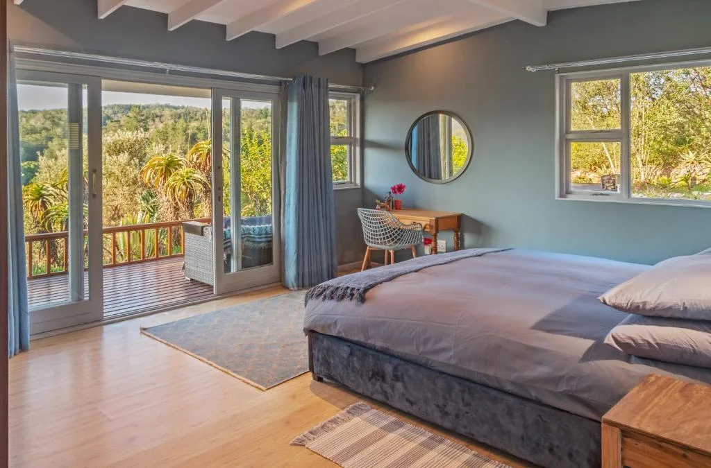 Spacious bedroom with bed, desk, and sliding doors overlooking forest views