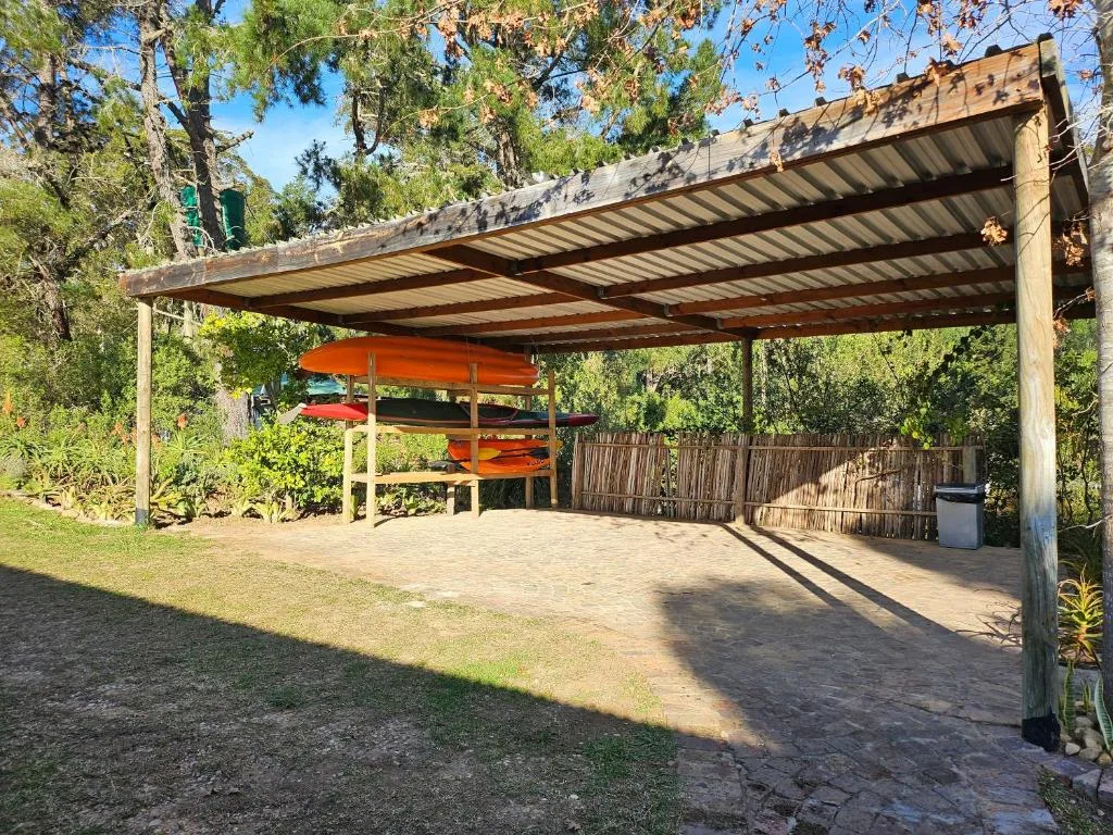 Covered outdoor patio with metal pergola and kayak storage in garden