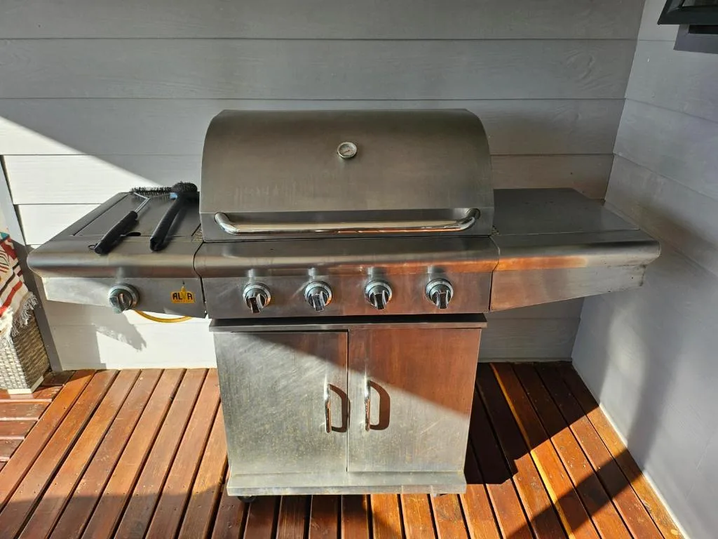 Stainless steel gas braai on wooden deck with storage cabinet below