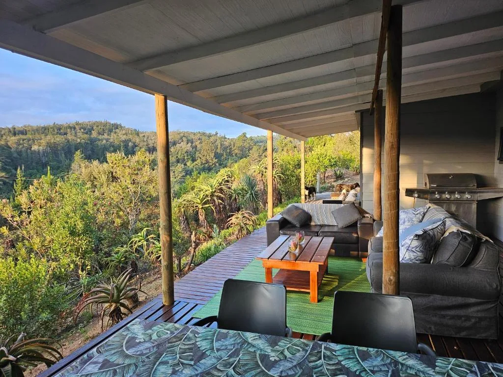 Covered deck with forest views, seating, braai grill, and dining furniture
