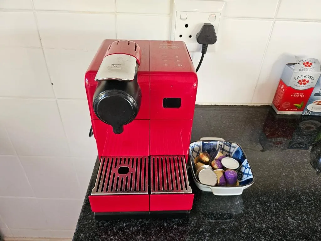 Red espresso machine with capsules and accessories on kitchen counter