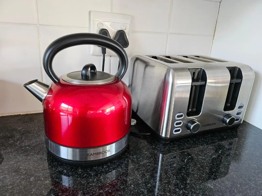 Red kettle and stainless steel toaster on dark kitchen countertop