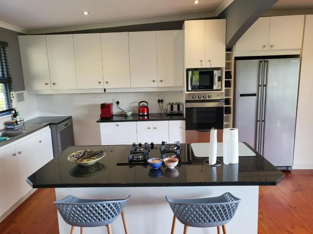 Modern kitchen with white cabinetry, black countertop, stainless steel appliances
