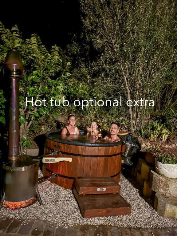 Wooden hot tub at night with guests relaxing surrounded by lush garden foliage
