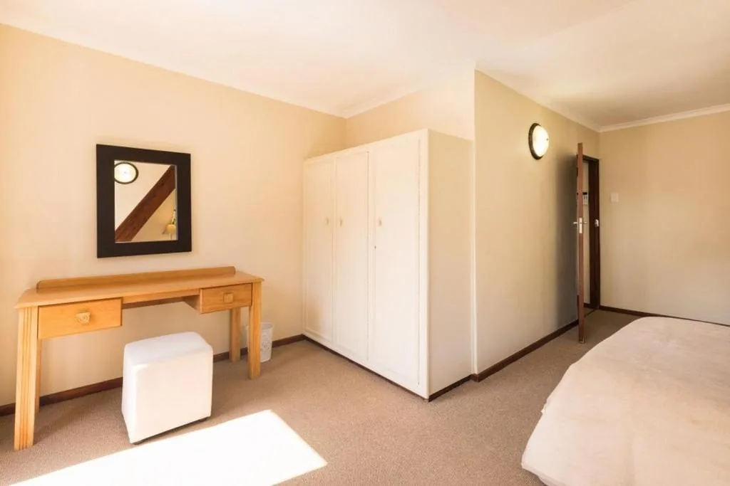 Spacious bedroom with twin beds, wooden desk, and built-in wardrobe