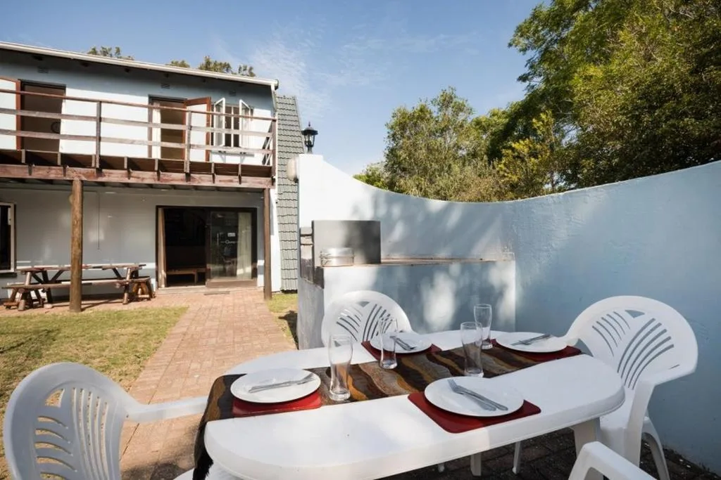Outdoor dining area with set table and white chairs overlooking property