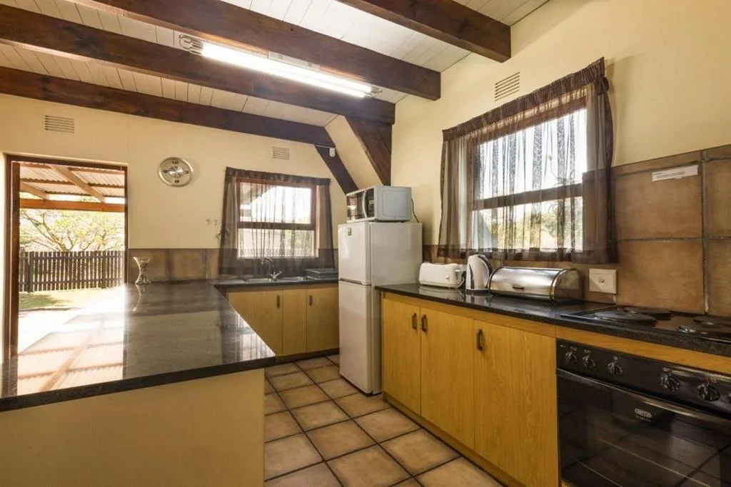 Spacious kitchen with wooden cabinetry, stove, fridge, and garden views