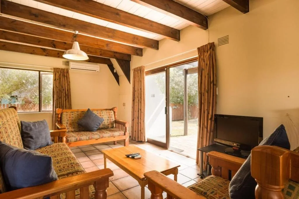 Spacious lounge with wooden beams, comfortable seating, and garden views