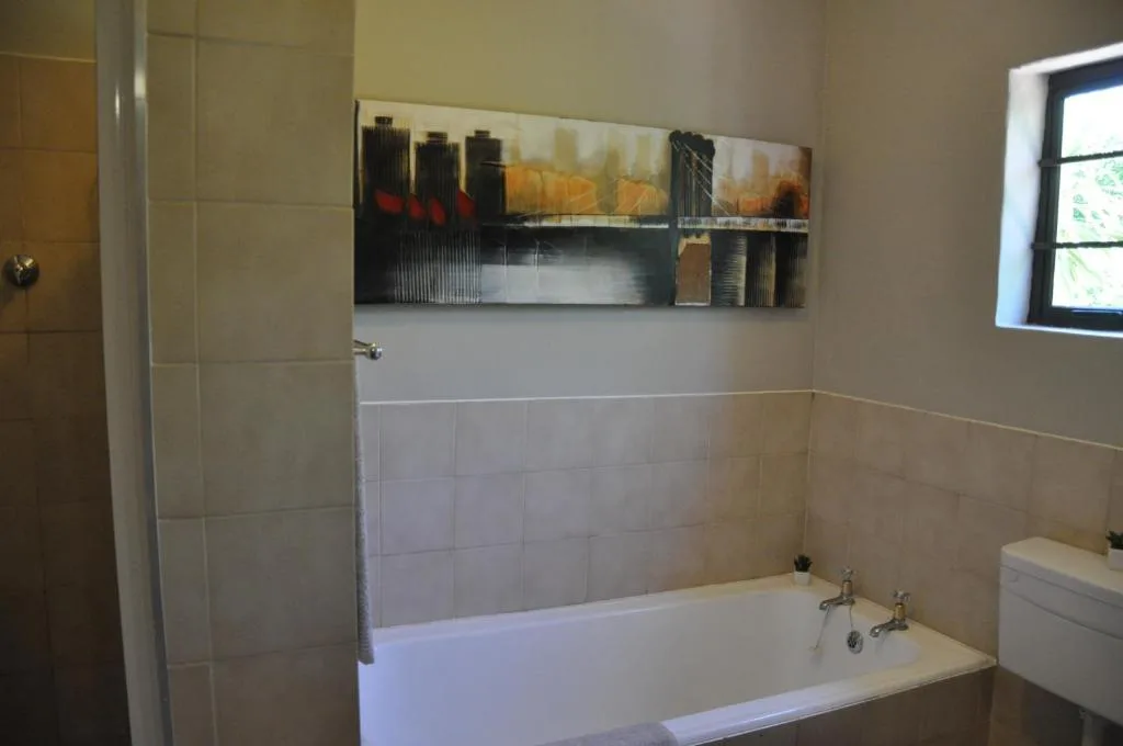 Modern bathroom with white bathtub, tiled walls, and urban artwork