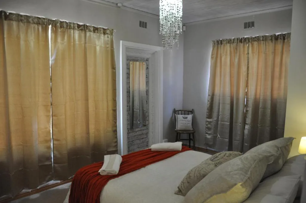 Spacious bedroom with queen bed, gold curtains, crystal chandelier