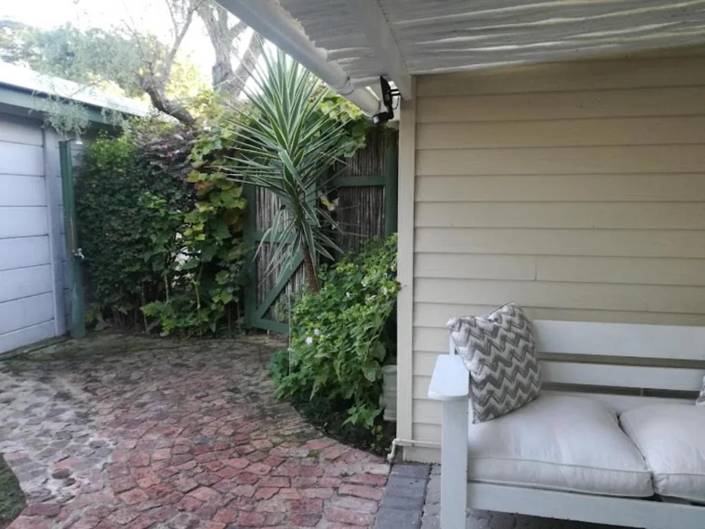 Shaded patio with seating, lush greenery, and brick paving area