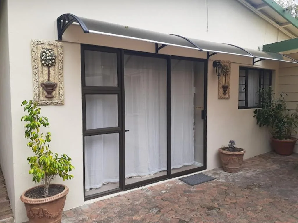 Cream cottage exterior with black-framed sliding doors and potted plants