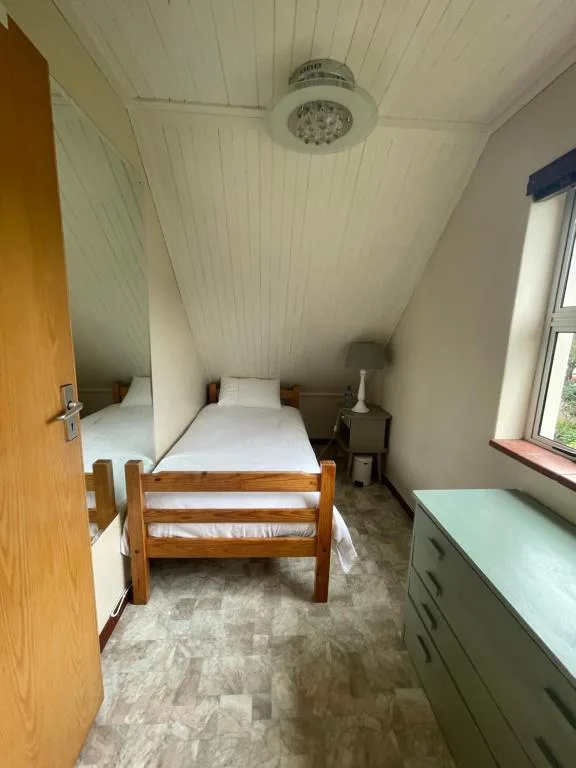 Cozy bedroom with wooden bed and sloped ceiling in cottage