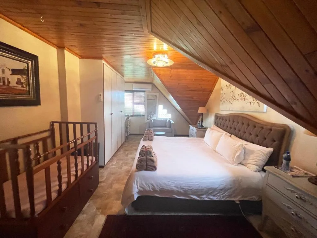 Upstairs bedroom with queen bed, wooden ceiling, and crib in loft space
