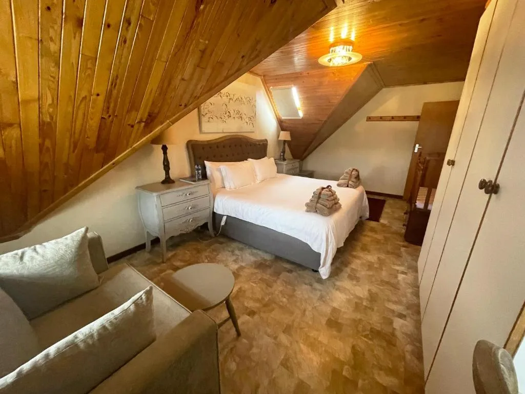 Spacious attic bedroom with wooden ceiling and queen bed
