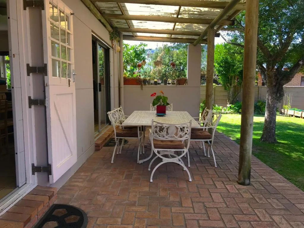 Covered patio with dining table, chairs, and garden views