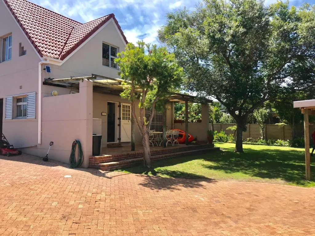 Pink cottage with red-tiled roof, brick patio, shaded deck and mature trees