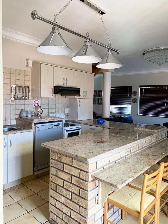 Modern kitchen with white cabinetry, granite countertop island, and industrial pendant lights