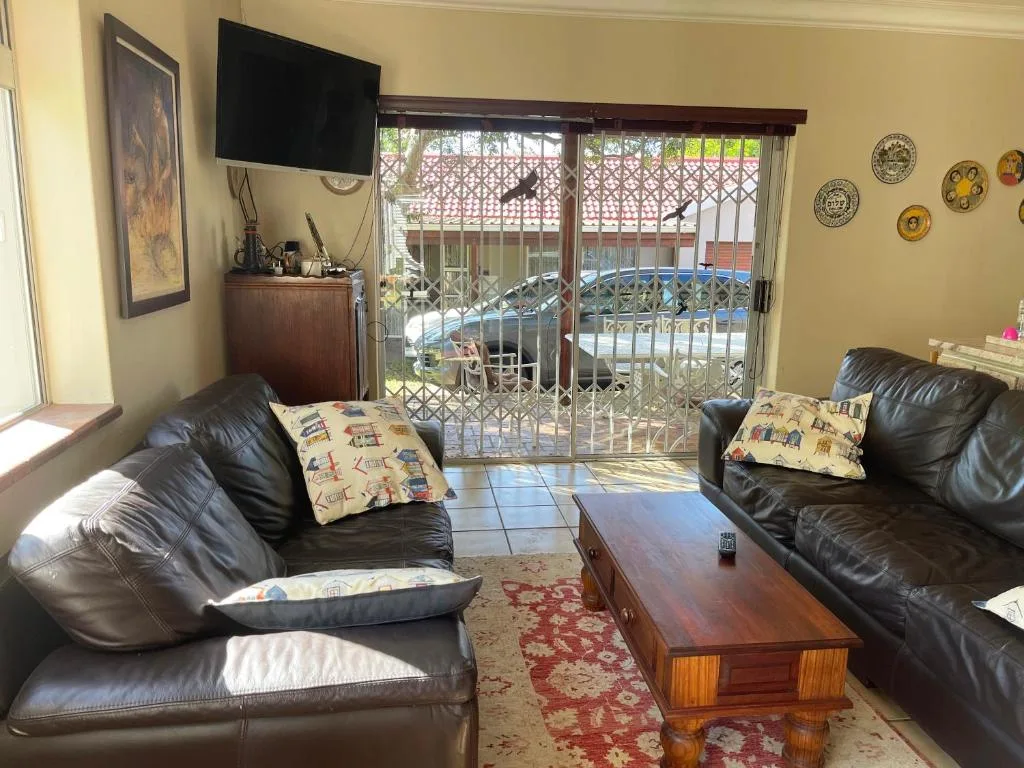 Comfortable lounge with black leather sofas and sliding doors to deck area