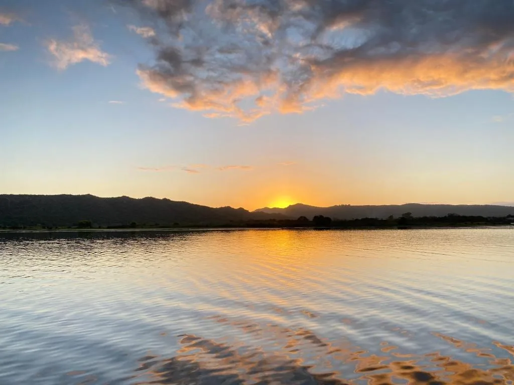 Sunset over calm lagoon with mountains silhouetted against golden sky