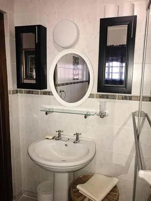 Clean bathroom with pedestal sink, round mirror, and black storage cabinets