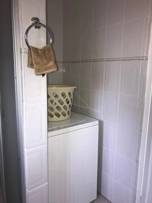 Small bathroom corner with tiled walls, towel ring, and decorative basket