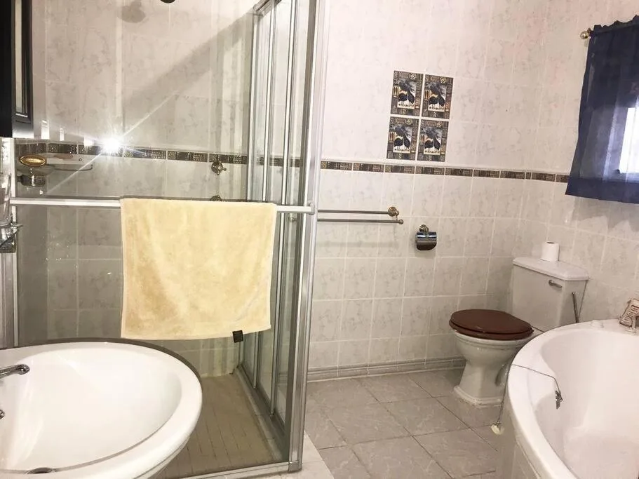 Spacious bathroom with shower enclosure, dual vanities, and toilet
