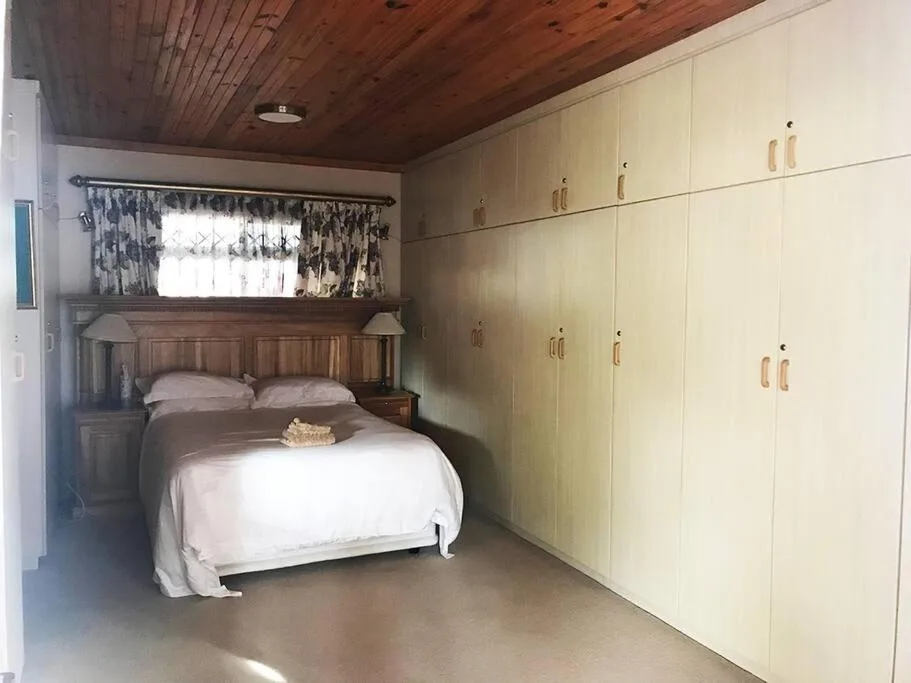 Bedroom with wooden bed, cream cabinetry, and wooden ceiling