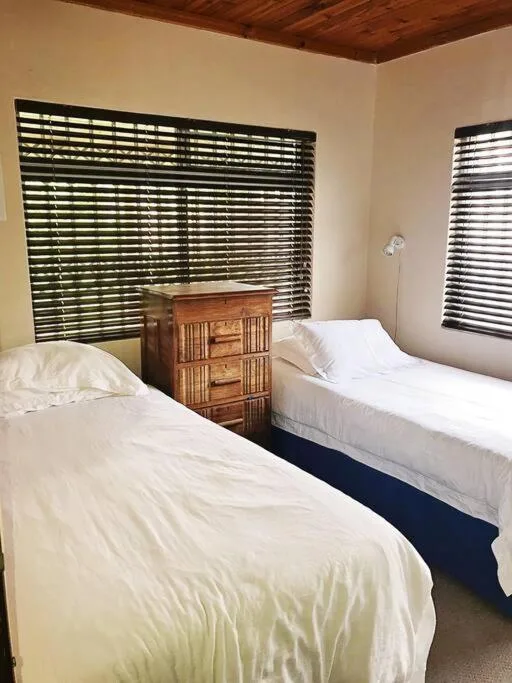 Twin beds with white linens and wooden bedside table between them