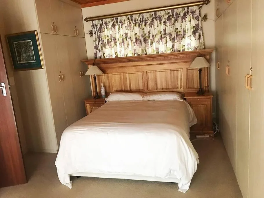 Spacious bedroom with wooden bed frame and white linens