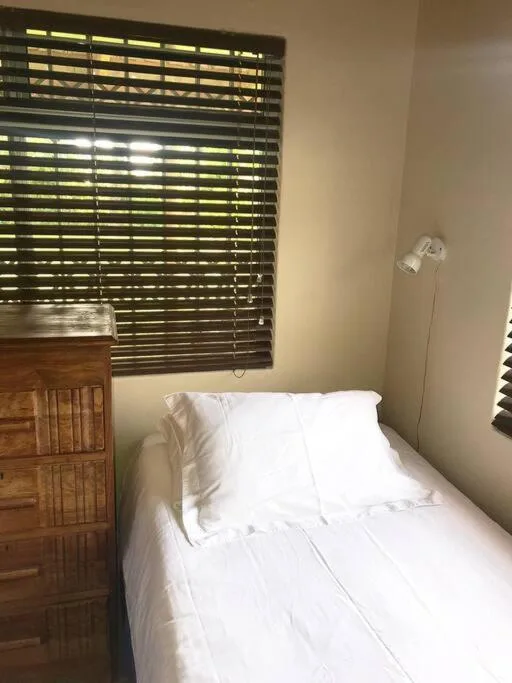 Bright bedroom with white bedding and wooden nightstand near window