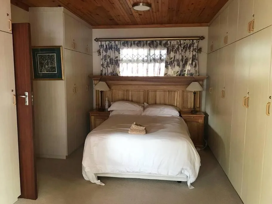 Cozy bedroom with wooden bed frame, white linens, and patterned curtains